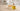 Unlabeled glass bottle of golden chamomile oil beside a handmade soap bar and a few chamomile flowers on a light neutral worktable in bright natural light, with a softly blurred modern workshop background.