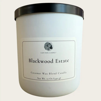 White candle with black lid labeled 'Blackwood Estate' on a light beige background