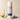 Carioca Nights body powder canister with a pear, vanilla bean, and flowers on a beige background