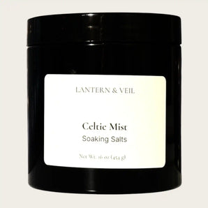 Black container of 'Celtic Mist' soaking salts by Lantern & Veil on a light gray background