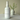 White bottle of 'Melon Mist' fragrance mist with a vase in the background on a neutral surface