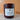 A candle in a matte wine jar with a white label reading 'Midnight Harvest' set against a warm autumn color background.