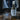 A black bottle of Lantern & Veil 'Still Occupied' room and linen spray, set on a rustic wooden table with a window and misty curtains in the background.
