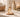 Glass fragrance mist bottle on a marble bathroom counter with a lit candle and rolled towels in the background