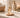 Glass fragrance mist bottle on a marble bathroom counter with a lit candle and rolled towels in the background