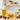 Jojoba oil in a glass bottle and bowl with jojoba seeds and green leaves on a bright, neutral workspace, styled for natural soapmaking ingredients.