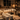 Candle studio workspace at night with multiple white candles in various stages on a wooden table, wax melter, fragrance bottles, and warm ambient lighting