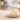 Mango butter in a small dish on a wood table with a bar of saop in background.
