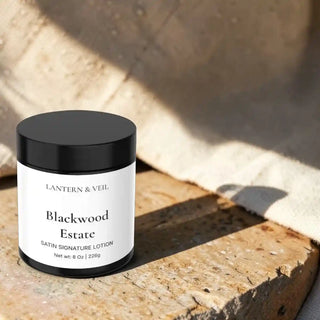 Lantern & Veil Blackwood Estate satin signature lotion jar on a wooden surface with natural light