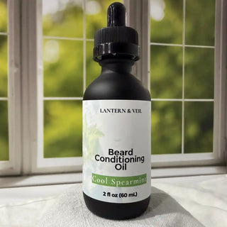 Bottle of Lantern & Veil Beard Conditioning Oil with a dropper on a surface in front of a window with greenery.