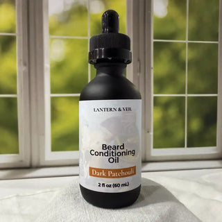 Bottle of Lantern & Veil Dark Patchouli Beard Conditioning Oil on a surface with a window in the background.