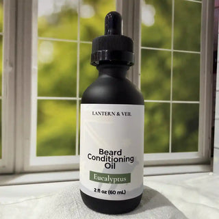 Bottle of Lantern & Veil Beard Conditioning Oil with Eucalyptus scent on a windowsill.
