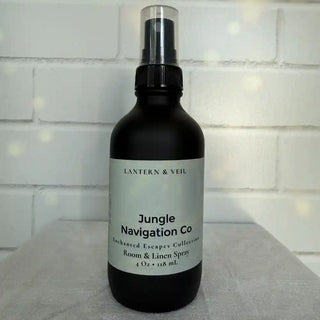 Room & Linen Spray bottle labeled 'Jungle Navigation Co' by Lantern & Veil on a textured surface with a tiled wall background.