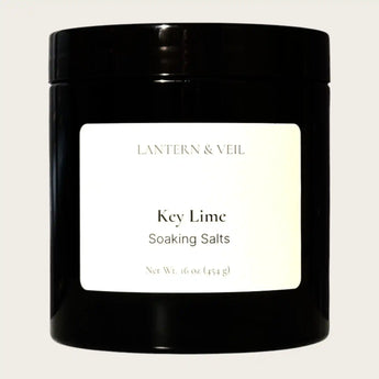 Black container of 'Key Lime Soaking Salts' by Lantern & Veil on a light gray background