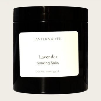 Black container of 'Lavender Soaking Salts' by Lantern & Veil on a beige background