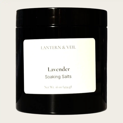 Black container of 'Lavender Soaking Salts' by Lantern & Veil on a beige background