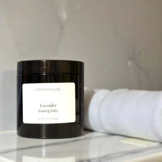 Black container of lavender soaking salts on a marble surface with a blurred background