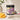 Jar of Mango Dragonfruit sugar scrub with mango and dragonfruit on a neutral background