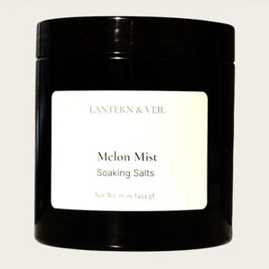 Black container of 'Melon Mist' soaking salts by Lantern & Veil on a beige background