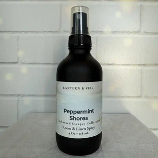 Black spray bottle labeled 'Peppermint Shores' by Lantern & Veil on a white surface with a tiled wall background.