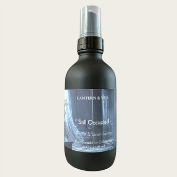 A 4 oz room and linen spray bottle by Lantern & Veil, featuring a matte black bottle, set against a solid off-white background.