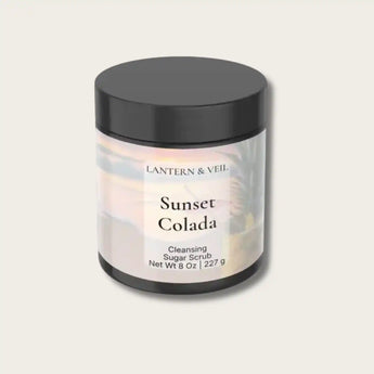 Cleansing sugar scrub jar labeled 'Sunset Colada' by Lantern & Veil on a light gray background
