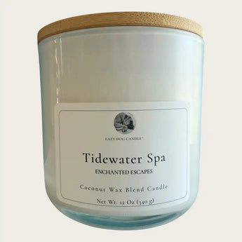 A white glass jar candle with a light wood lid, featuring a white label that reads 'Tidewater Spa Enchanted Escapes' 