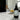 Bottle of 'Tiki Treats' room and linen spray on a marble surface with a blurred background with a tiki and pineapples and ice cream.
