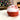 Red and white bath bomb on a surface with a Christmas tree and fireplace in the background